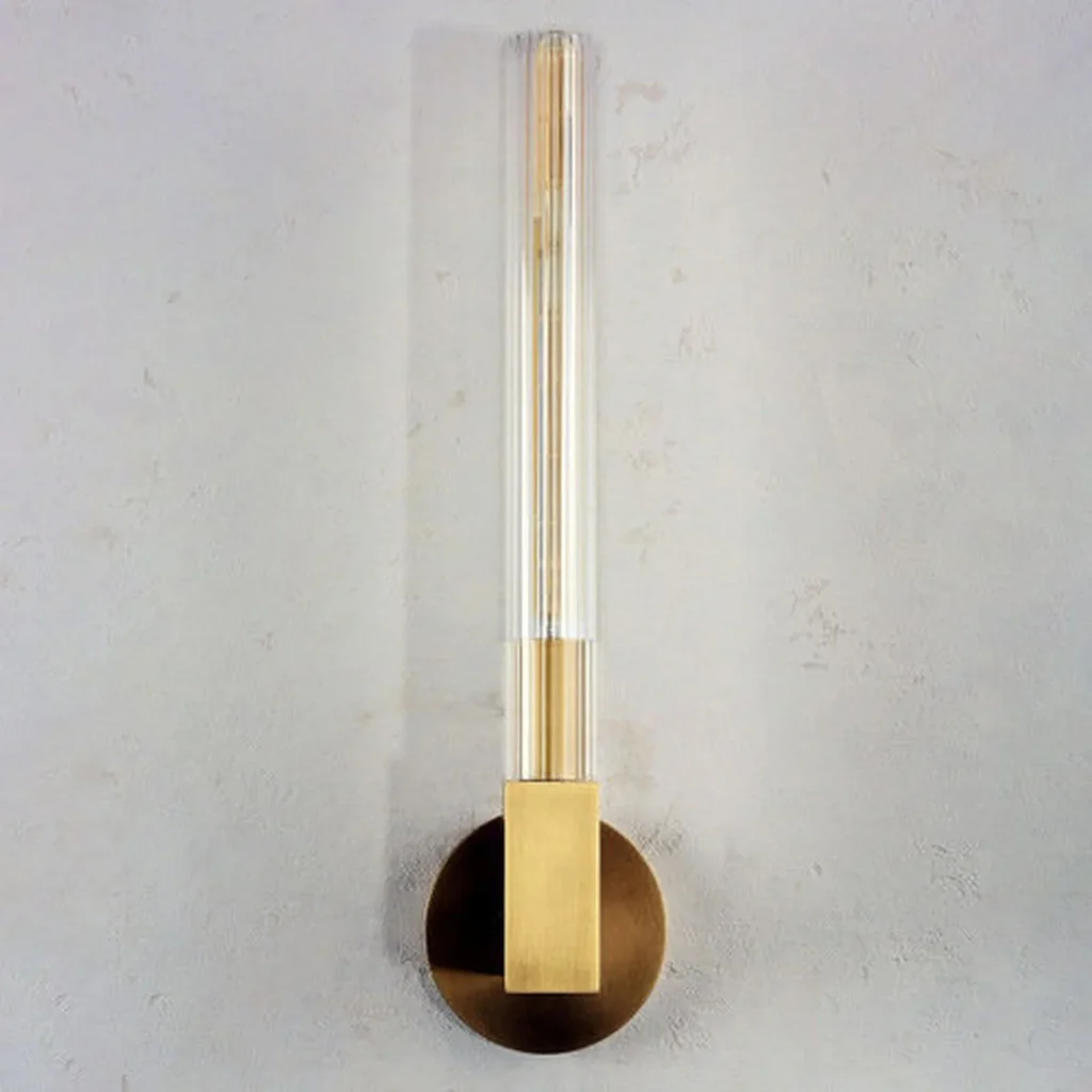 Front view of an unlit brass wall sconce with a clear glass tube