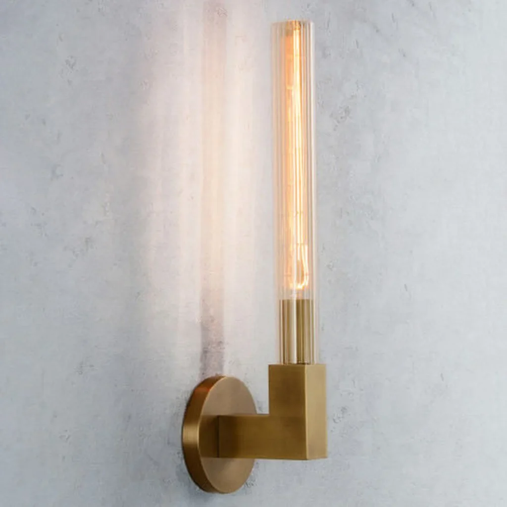 Side view of a glowing brass wall sconce with a clear glass tube